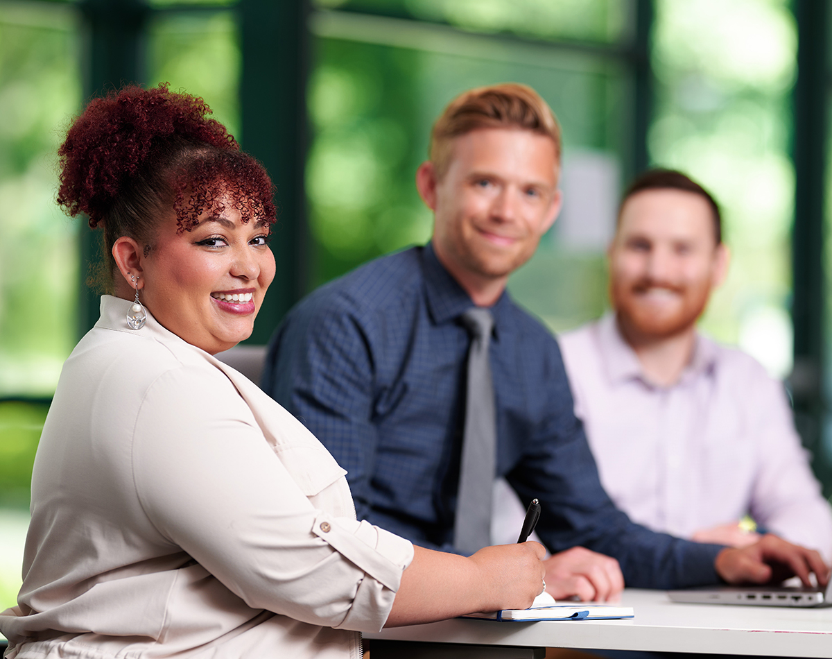 A group of professionals meeting while smiling at the camera.